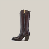 The Francia Rings Tall Shaft Chocolate - J Toe boot is crafted from premium leather, featuring a tall, chocolate silhouette with a side zipper and decorative back stitching. Its pointed toe and chunky heel embody understated luxury against a plain white background.