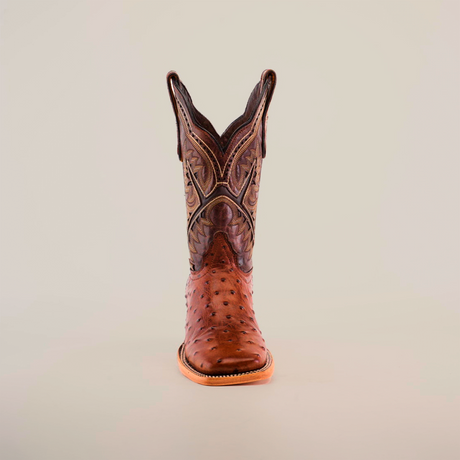 A single chocolate cowboy boot, made from premium materials, stands upright against a plain white background. It features intricate stitching and patterns with a distinctive Karoo Ostrich Print, square toe, and tall shaft.