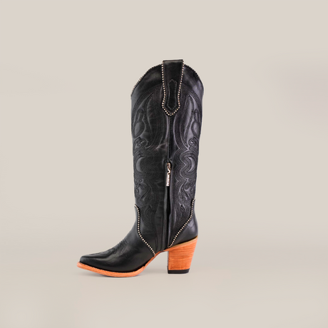 A single Linda Studs Tall Shaft Black - J Toe boot from the Platinum Collection features a wooden block heel and intricate patterns with silver studs, against a plain white background.