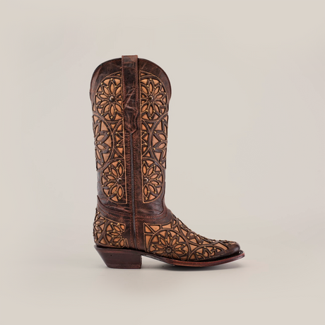 The Vitralli Studs Tabaco boot, a handcrafted ornate cowboy boot with intricate floral patterns and a dark brown finish, is displayed in a side profile against a plain white background, highlighting its exquisite design.