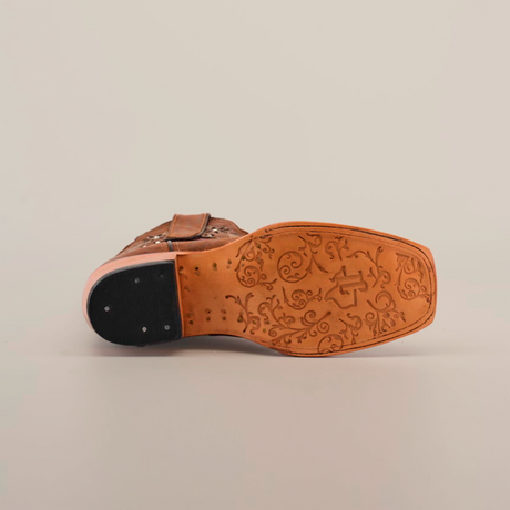 Bottom view of the Grecas Orix - Short Shaft - Narrow Square Toe boot reveals a tan sole with floral designs and a dark heel, elegantly contrasted against a plain white background.