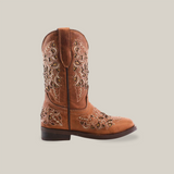 The Kiara Studs Fawn - Square Toe cowboy boot, crafted from premium brown leather, showcases intricate floral embroidery on the shaft and foot. With a low heel and pull tabs, it provides style and ease for fashion-forward young girls seeking standout pieces against a plain white background.