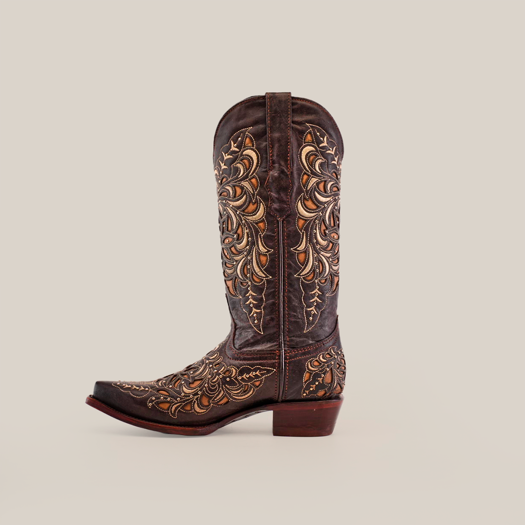 The Kiara Crystals Chocolate boot features gold and tan embroidery on a brown backdrop, set against a plain white background. With a low heel and snip toe, this handcrafted western boot captures the essence of cowboy footwear perfectly.