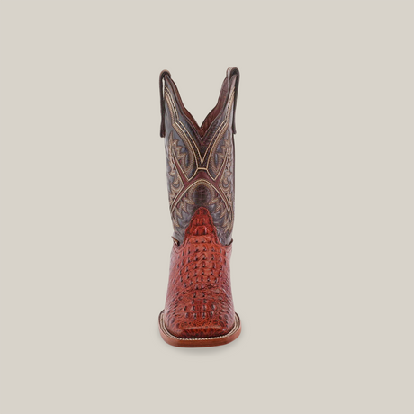 Front view of a handcrafted cowboy boot with intricate brown and red stitching. The Caiman Hornback Print Cogñac texture in premium cowhide leather features a pointed toe and high V-shaped shaft, set against a white background. Product: Caiman Hornback Print Cogñac - Square Toe.