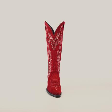 A single bright red cowboy boot made from luxurious suede leather with intricate embroidery and decorative stitching on a plain white background. The womens boot has a pointed toe and high, flared top, akin to the Amara Red Suede - Tall Shaft - Snip Toe boots.