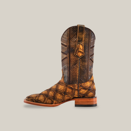 The Big Bass Pirarucu Print Rustic Honey features a square toe, premium cowhide with textured patterns, detailed stitching, and pull strap. Finished with a light brown sole and darker heel, this handcrafted boot is displayed on a white background.