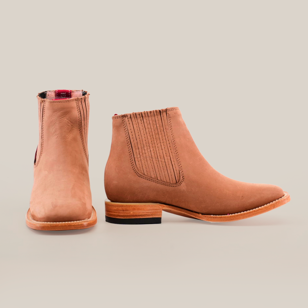 Displayed against a plain white background are the Prime Suede Sand Square Toe boots. The left boot is shown front-on and the right from the side, highlighting an elastic panel and wooden sole—ideal for any fashion-forward wardrobe.