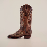 The Texas Cross Glitterbomb Brown boot, crafted from premium leather, features intricate wing embroidery, a low heel, and a pull strap. Designed by master bootmakers in a narrow square toe style against a simple white background.