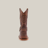 A single handcrafted boot in Matte Brown Country Stitch - Square Toe is presented from the side against a white background, featuring ornate patterns on premium cowhide, a distinctive wooden heel, and decorative elements around the ankle.