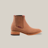 The Prime Suede Sand Square Toe boot is a tan leather Chelsea style featuring an elastic side panel, a wooden heel, subtle stitching, and a slightly pointed toe. It embodies the Cowboy Fashion trend against a plain white backdrop.