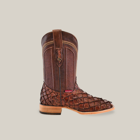 The Exotic Piraruco Fish cowboy boot in matte brown leather, with a square toe, features a textured scale design. It stands upright against a plain white background, showcasing its light wooden sole and red ankle tag.