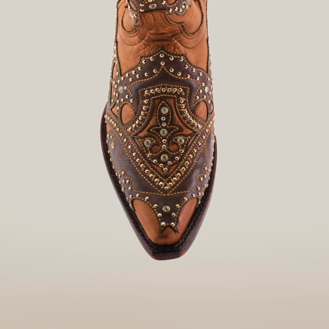 A close-up of the Nirvana Tabaco Short Shaft Snip Toe womens cowboy boot highlights its beautifully designed brown leather, ornate patterns, decorative studs, detailed stitching, and elaborate artwork for an elegant Western-inspired appearance.