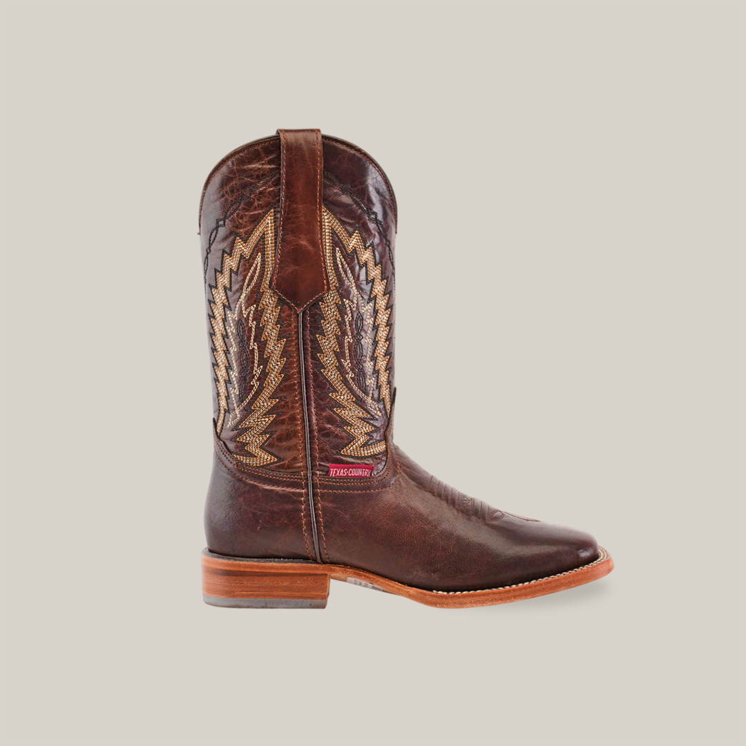 The Dessert Camel - Square Toe boot features intricate stitching with light brown and beige threads on premium cowhide. It has a square toe, wooden sole, and a red label near the top, showcasing timeless elegance against a plain white background.