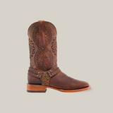 The Matte Brown Country Stitch boot is handcrafted with premium cowhide, featuring intricate circular embroidery, decorative straps with a brass buckle, a medium-height wooden heel, and a square toe for that perfect country flair.