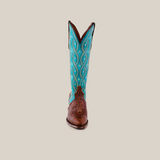 The Premier Tabaco Handtooled Flowers boot showcases Western elegance with its brown leather foot and a tall blue shaft, featuring intricate stitching and floral tooling. Small decorative details enhance its pristine white background.