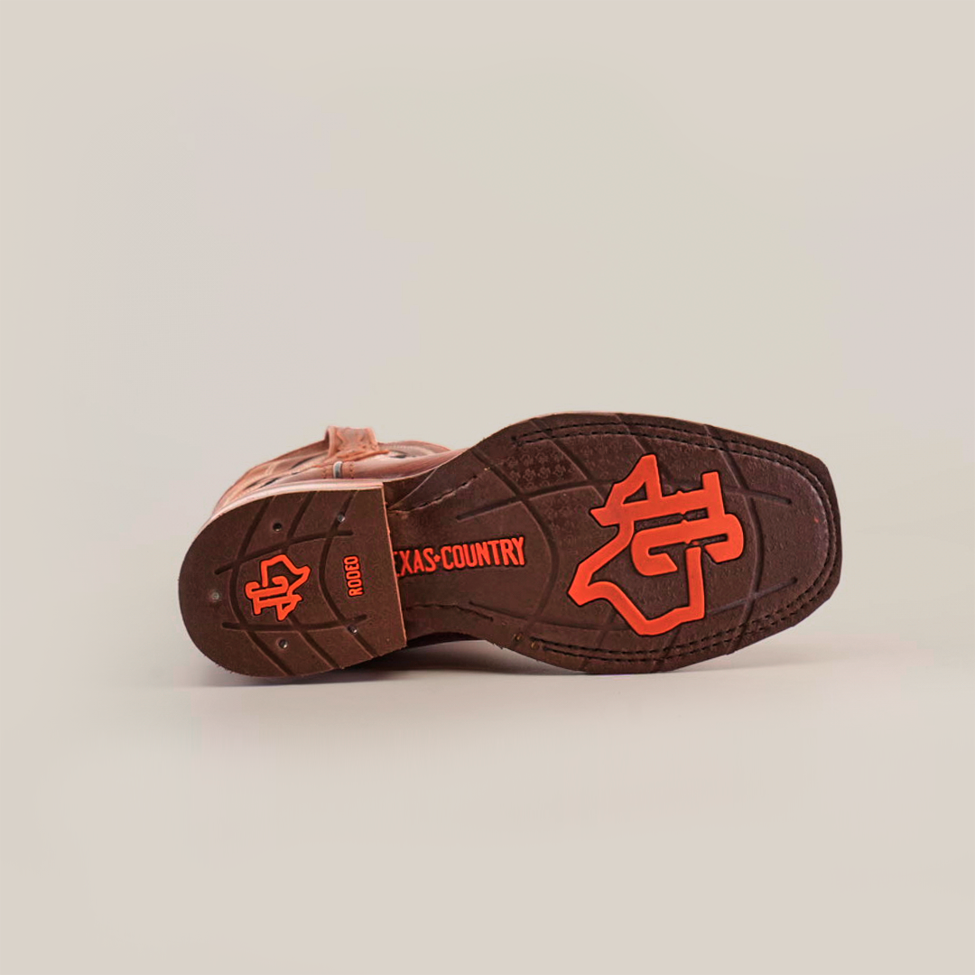 The image shows the slip-resistant sole of a Fresno Shedron Slip Resistant Sole Rodeo Toe cowboy boot, featuring red text and symbols. It highlights NGD, TEXAS COUNTRY, and a logo with a cowboy hat and Texas outline on a white background that accentuates each detail.