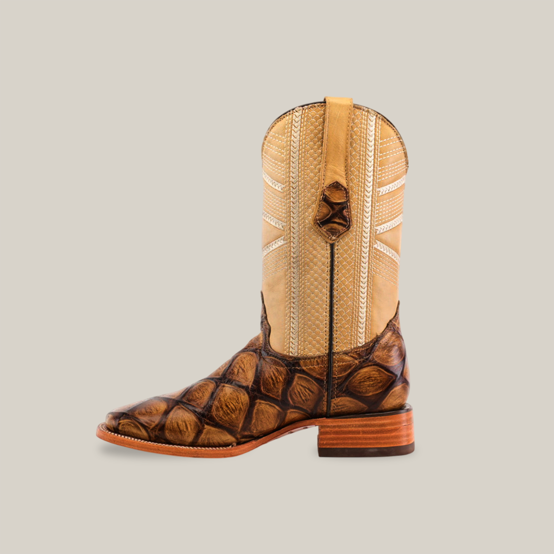 The Big Bass Pirarucu Print Rough Orix - Square Toe cowboy boot features a tan upper with detailed stitching and a textured brown lower resembling scales, set against a white background. It includes a wooden heel, pull tab, and showcases classic premium cowhide craftsmanship.