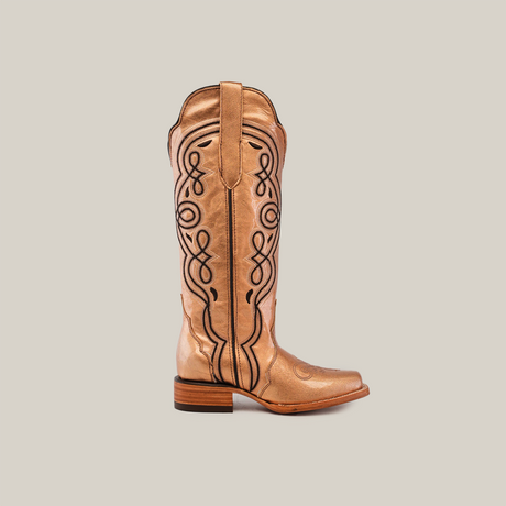 A single Eden Rose Gold cowboy boot with intricate black embroidery on a shiny surface, featuring a wooden heel and narrow square toe, set against a plain gray background.