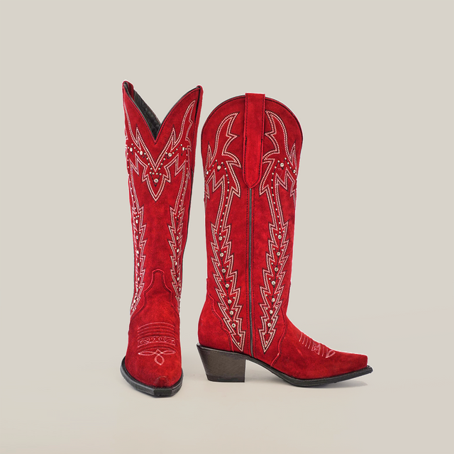 The Amara Red Suede - Tall Shaft - Snip Toe womens boots, in vibrant red, showcase intricate white embroidery and sleek black heels. Set against a plain white background, these boots feature pointed toes and elegant decorative patterns along the shaft.