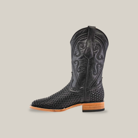 The Texas Basket Weave Black cowboy boot, crafted from premium cowhide leather, showcases intricate shaft embroidery and textured foot details. It features a wooden heel, square toe, and is set against a plain white background.