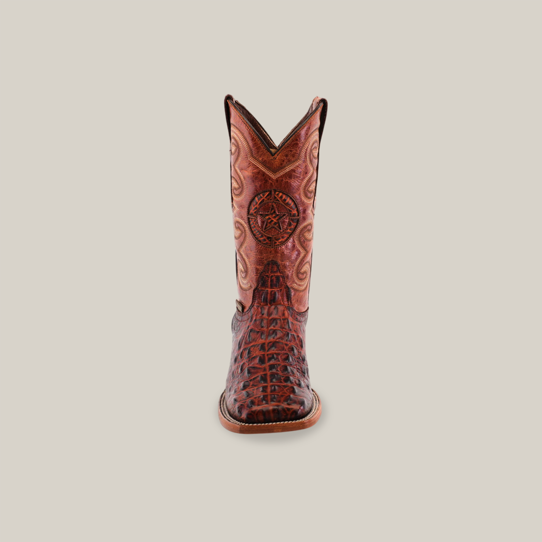 A single square toe cowboy boot in cogñac with a Morelet crocodile print, crafted from cowhide leather. It features intricate brown and red patterns and a star emblem on the shaft against a light background.